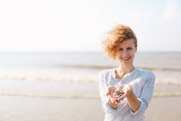 retrato de una mujer joven que muestra conchas marinas - sensory perception shell using senses women fotografías e imágenes de stock