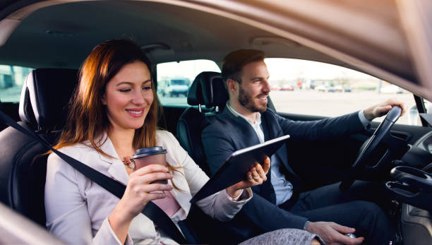 istock Businesswoman using digital tablet while businessman driving a car 678835816