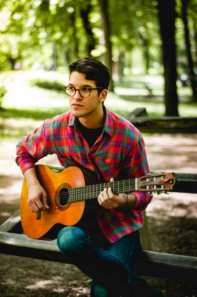 istock Man sitting and playing guitar in the park 678837022