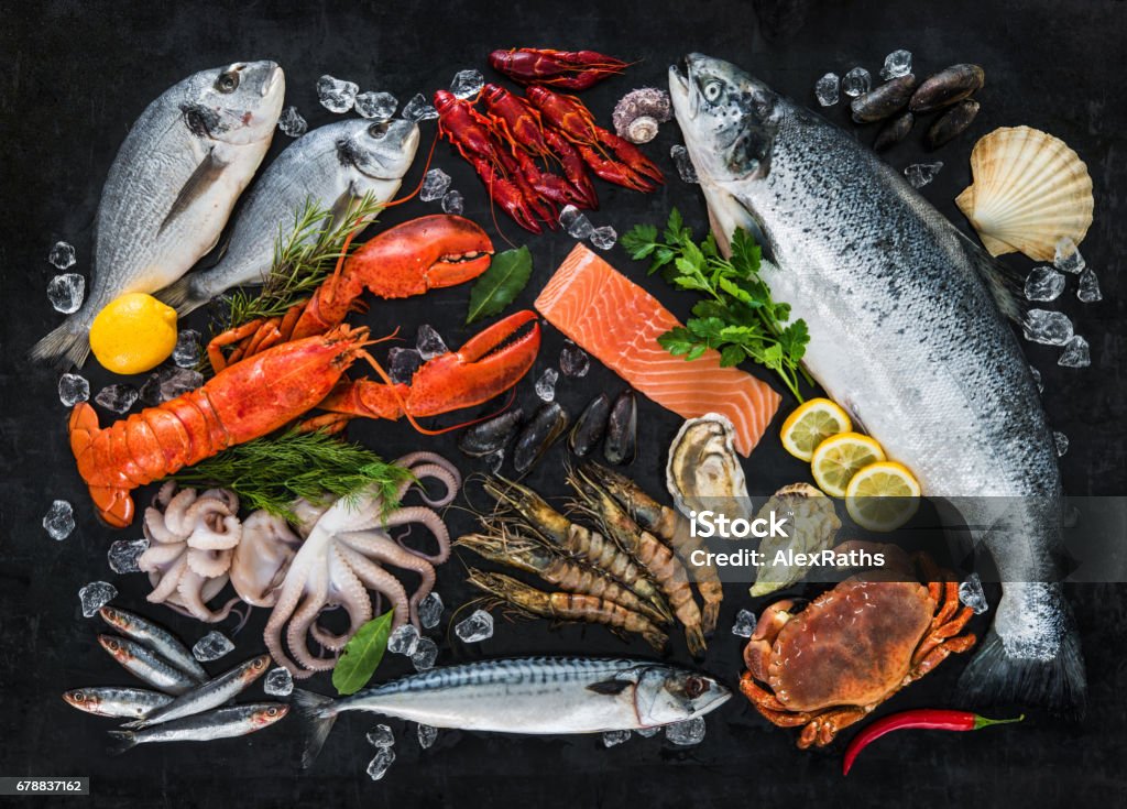 Fresh fish and seafood Fresh fish and seafood arrangement on black stone background Seafood Stock Photo
