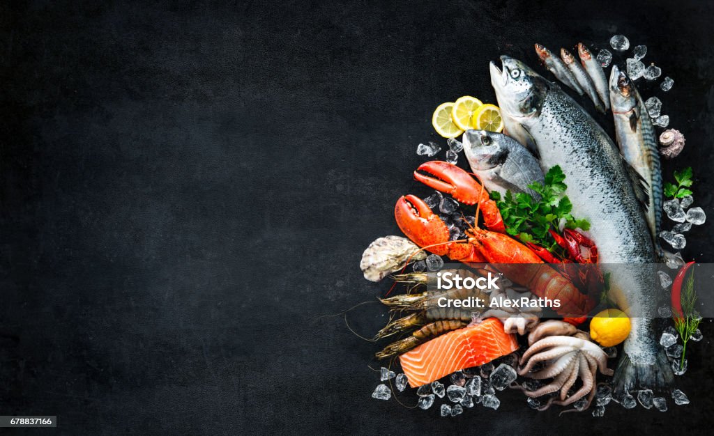 Fresh fish and seafood Fresh fish and seafood arrangement on black stone background Seafood Stock Photo