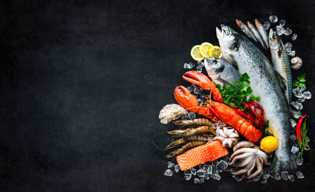 Fresh fish and seafood Fresh fish and seafood arrangement on black stone background catch of fish stock pictures, royalty-free photos & images