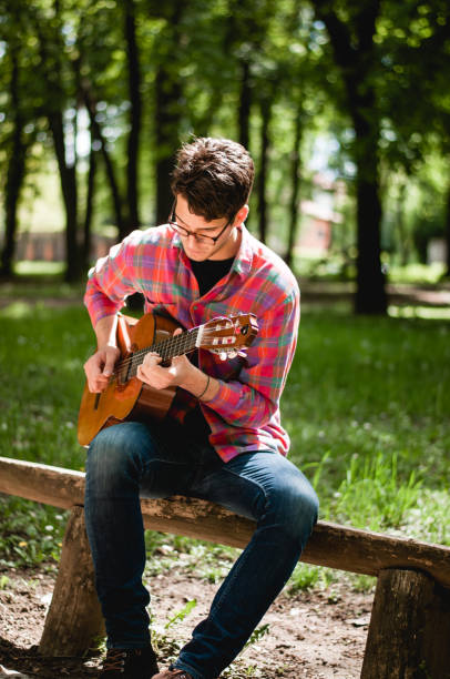 istock Man sitting and playing guitar in the park 678837210