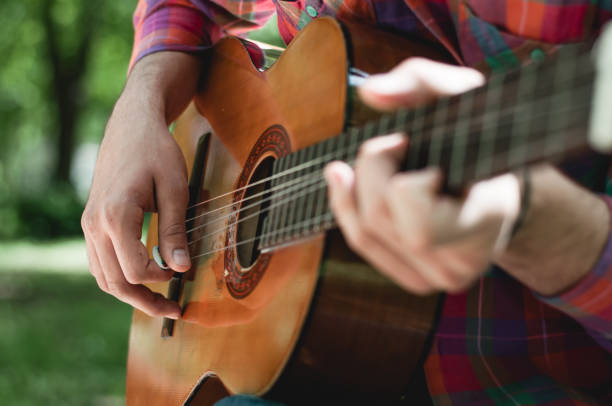 istock Man sitting and playing guitar in the park 678837296