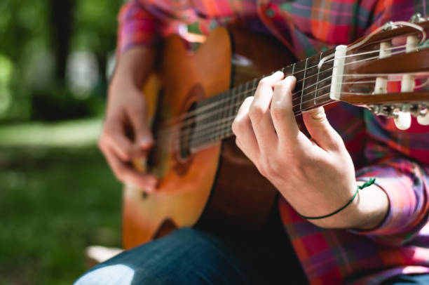 istock Man sitting and playing guitar in the park 678837898