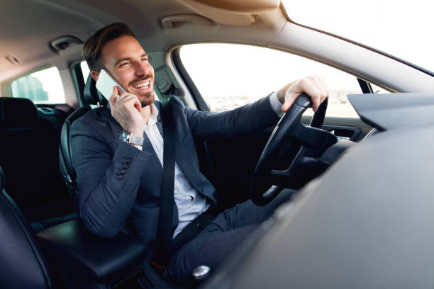 Businessman using mobile phone while driving a car stock photo