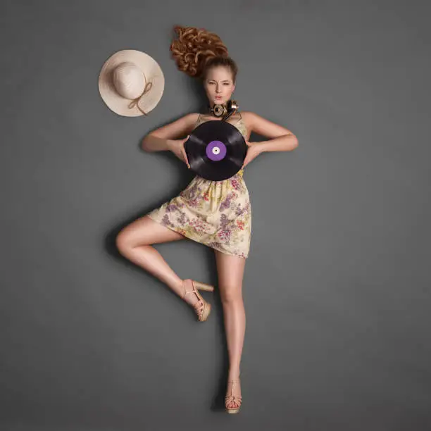 Beautiful girl, wearing vintage music headphones around his neck and holding a purple LP microgroove vinyl record on chalkboard background.