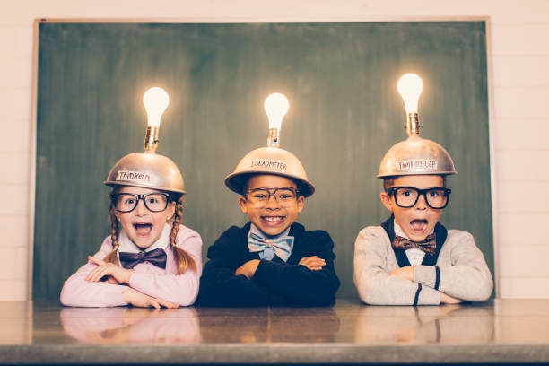 Three Young Nerds with Thinking Caps Three young nerds sit in a classroom setting with a thinking cap on their heads. They are suprised and smiling as their light bulbs are lit as the new ideas are flowing. They're wearing cardigans and bow ties. Learning is fun when you have ideas. helmet photos stock pictures, royalty-free photos & images