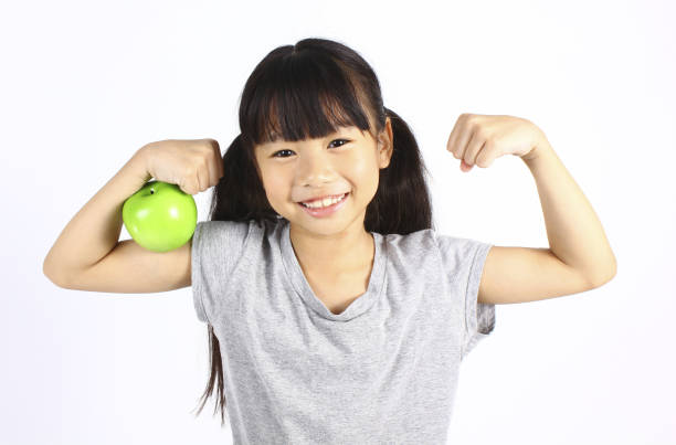 istock A little girl flexes her muscle while showing off the apple 678867374