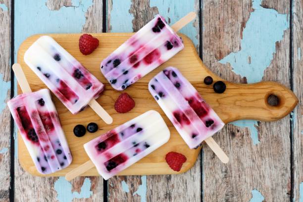 istock Mixed berry yogurt popsicles on a paddle board over rustic wood 678933804