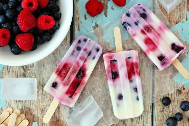 Photo of Mixed berry yogurt popsicles on a rustic wood background