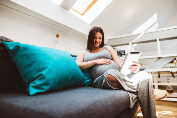 istock pregnant woman relaxing on the sofa using the computer 678939290