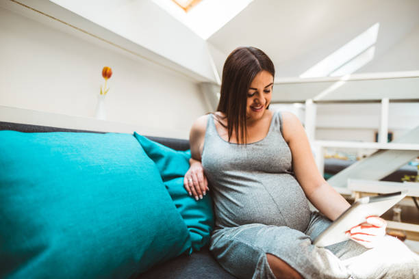 istock pregnant woman relaxing on the sofa using the computer 678940846