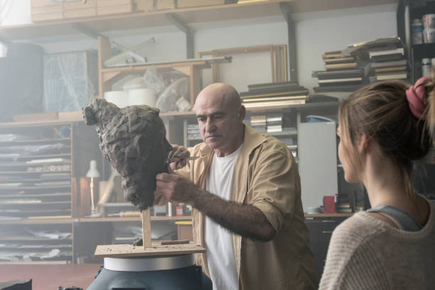 istock Teacher and student sculpting clay face 678962762