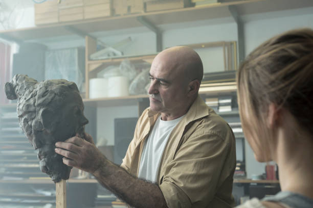 istock Teacher and student sculpting clay face 678965450