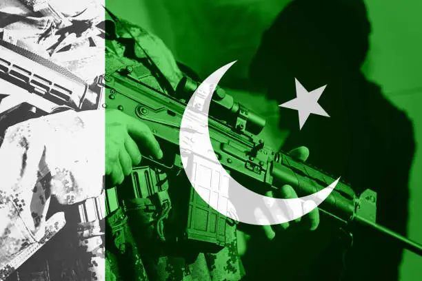 Soldier with machine gun with national flag of Pakistan