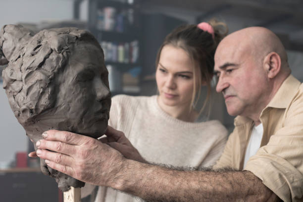 istock Teacher and student sculpting clay face 678974074