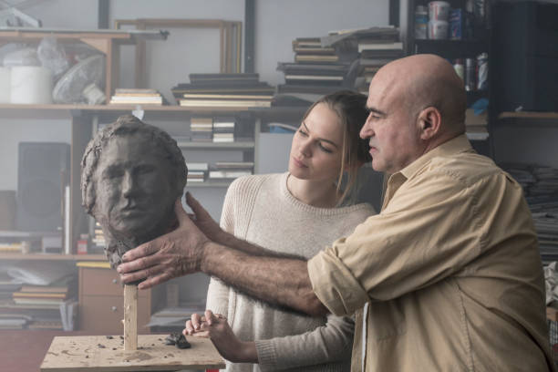 istock Teacher and student sculpting clay face 678974568