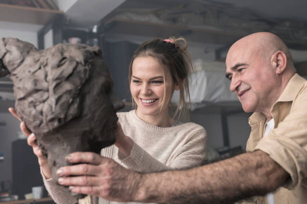 istock Teacher and student sculpting clay face 678974808