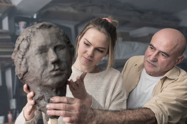 istock Teacher and student sculpting clay face 678975396
