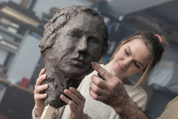 istock Teacher and student sculpting clay face 678980164