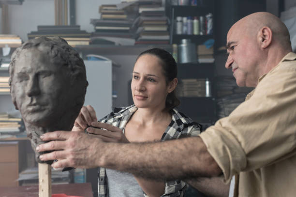 istock Teacher and student sculpting clay face 678980176