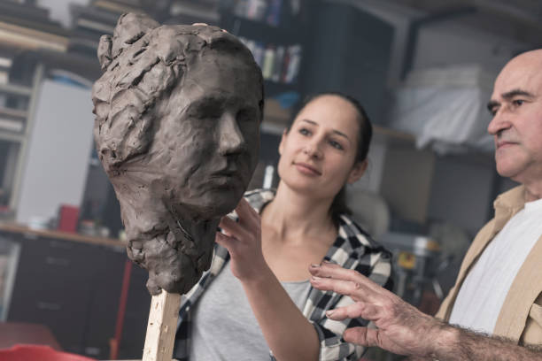 istock Teacher and student sculpting clay face 678981418