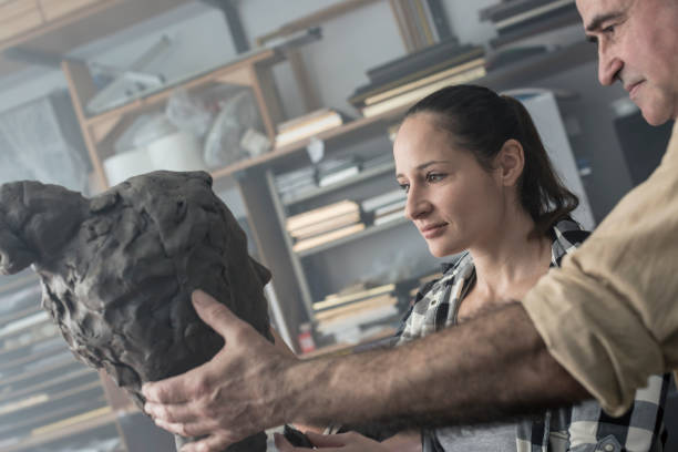 istock Teacher and student sculpting clay face 678982656