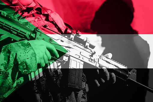 Soldier with machine gun with national flag of Sudan