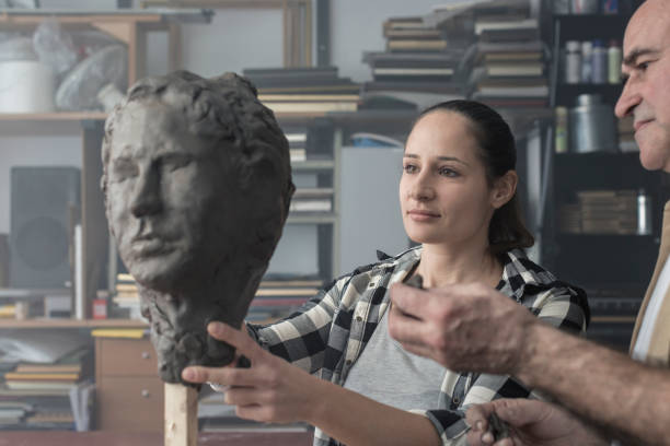 istock Teacher and student sculpting clay face 678984222