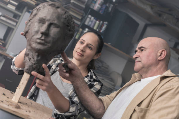 istock Teacher and student sculpting clay face 678984804