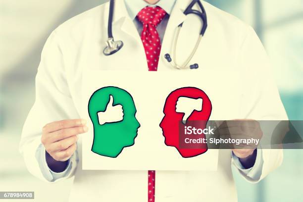 Doctor Hands Holding White Card With Green Red Thumbs Up Thumbs Down Symbols Inside Signs Shaped As Human Head Stock Photo - Download Image Now