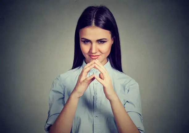 Let me think. Attractive woman looking with sly expression, having good idea