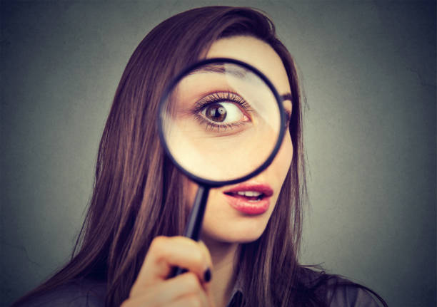 istock Curious woman looking through a magnifying glass 678985658