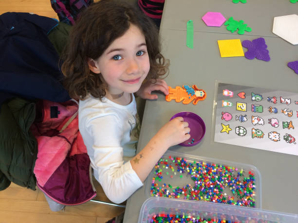 istock Young girl hand crafting with multicolored plastic pellets 679001068
