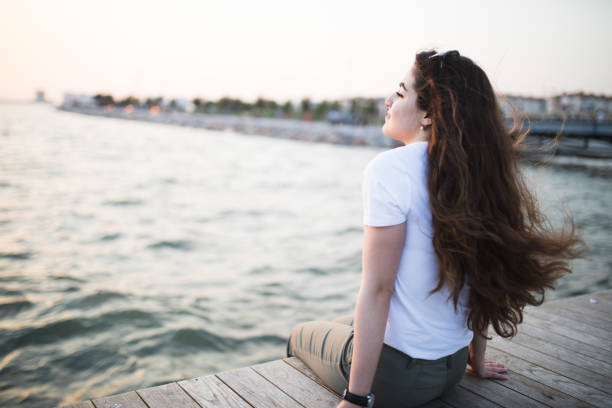 istock Young woman sitting looking sunset 679008576