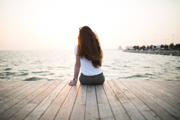 istock Young woman sitting looking sunset 679008822
