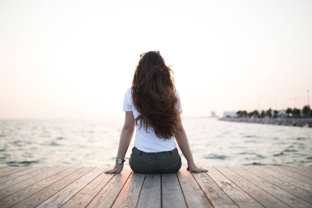 istock Young woman sitting looking sunset 679011800