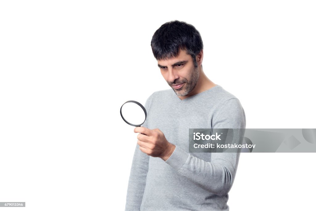 Dark-haired man looking with magnifying glass Dark-haired man looking with magnifying glass on white background Analyzing Stock Photo