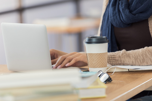 Unrecognizable college student uses a laptop in the campus library.