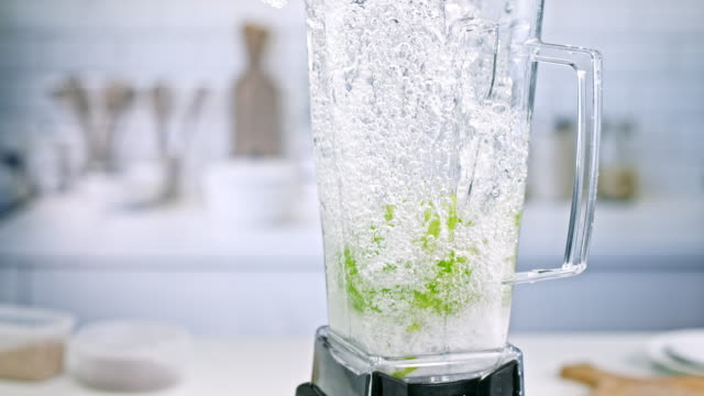 SLO MO Whole green apple and water mixing in blender