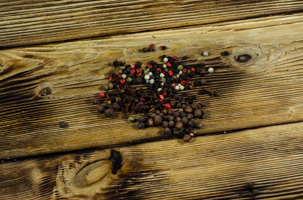 Different multicolored pepper spices on wooden table