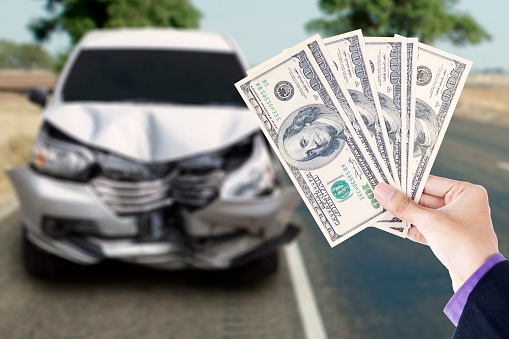 Hands of businessman holding currency dollars with a broken car in the highway