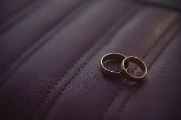 Wedding rings on a burgundy leather background inside the car