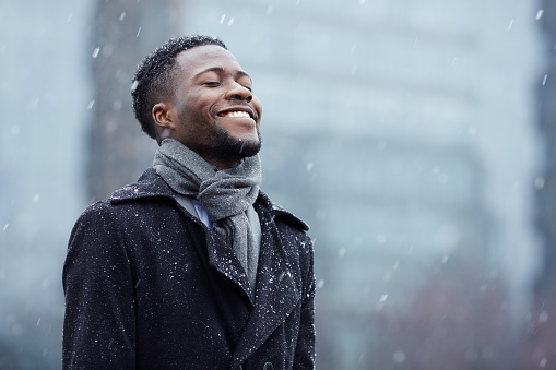 Cheerful man enjoying snowflakes falling from upwards