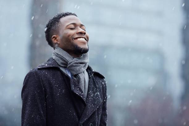 Happy man in snowfall Cheerful man enjoying snowflakes falling from upwards businessman happiness outdoors cheerful stock pictures, royalty-free photos & images