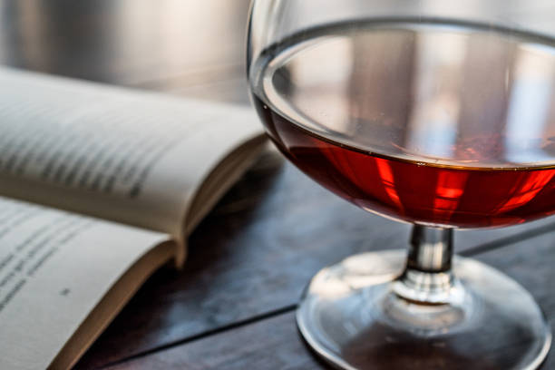 Glass of Cognac with a book on wooden surface. Beverage Concept.