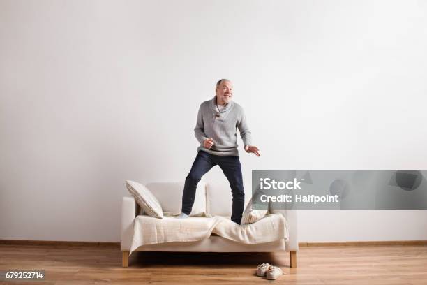 Handsome Senior Man Standing On Couch Dancing Studio Shot Stock Photo - Download Image Now