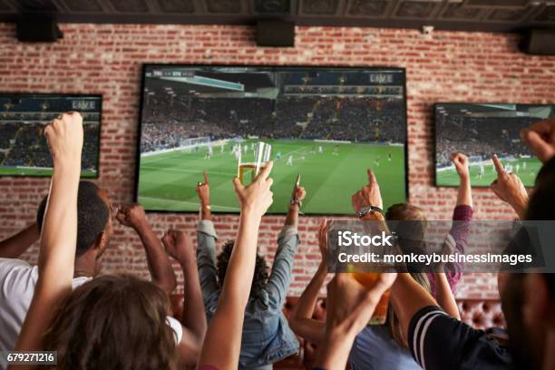 Rear View Of Friends Watching Game In Sports Bar On Screens Stock Photo - Download Image Now