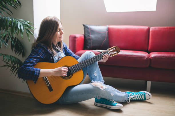 istock Young hipster girl playing guitar at cozy home interior 679276584